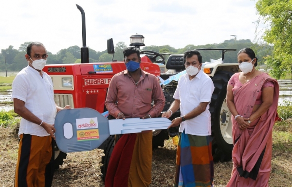 People’s Bank Chairman Sujeewa Rajapakse  giving away a loan grant under the Aswenna loan scheme to purchase a tractor. Acting CEO/General Manager Bonniface Silva  Anuradhapura Regional Manager Chandrika Nissanka also in the capture. 