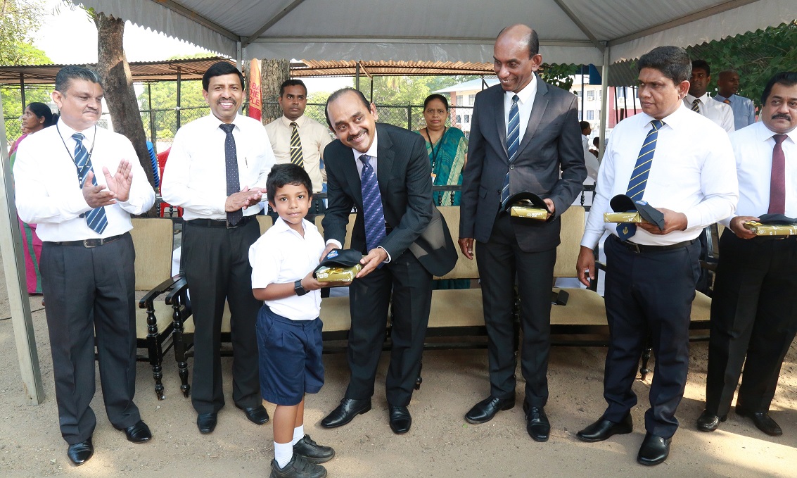 People’s Bank Chairman Sujeewa Rajapakse handing over a gift to student who made the first deposit